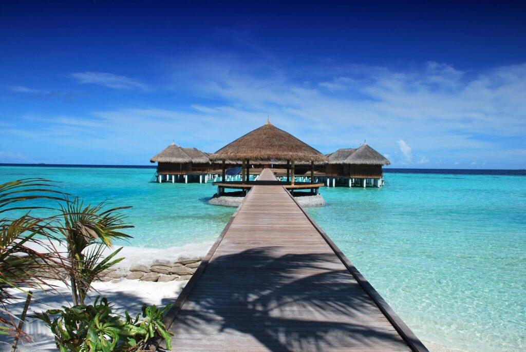 Scenic view of a wooden boardwalk leading to serene overwater bungalows at an island resort.