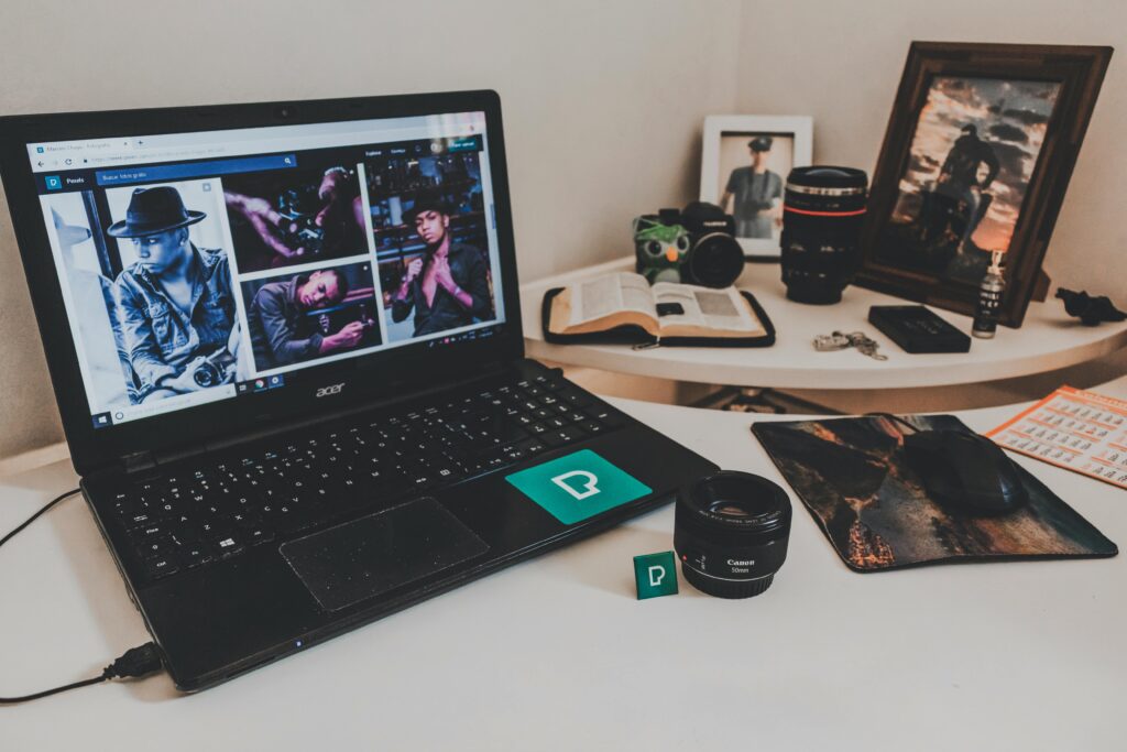 A modern workspace featuring a laptop, photography equipment, and an open book on a desk.